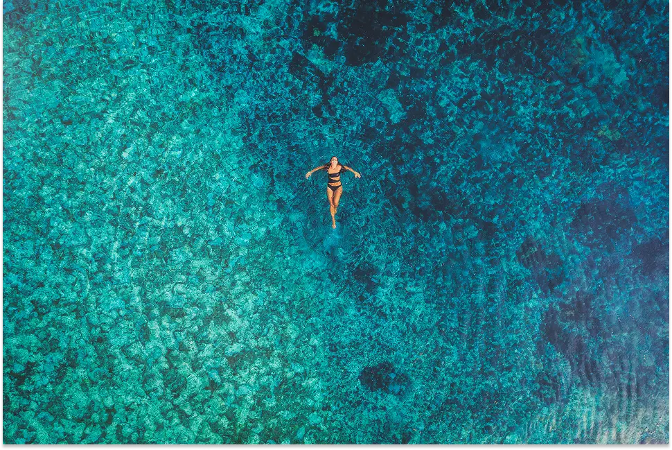 Donna che galleggia nell'acqua turchese cristallina. Vacanza rilassante in mare.