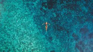 Donna che galleggia nell'acqua turchese. Relax e rigenerazione alle terme.