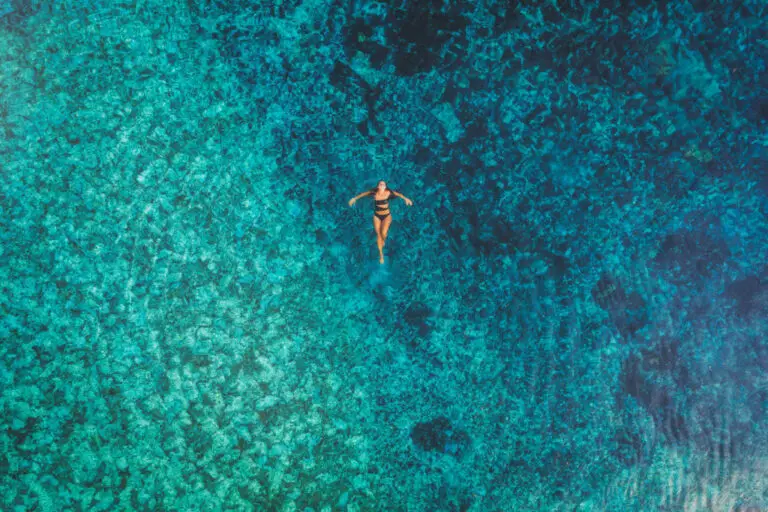 Donna che galleggia in acque cristalline. Relax e vacanza al club.