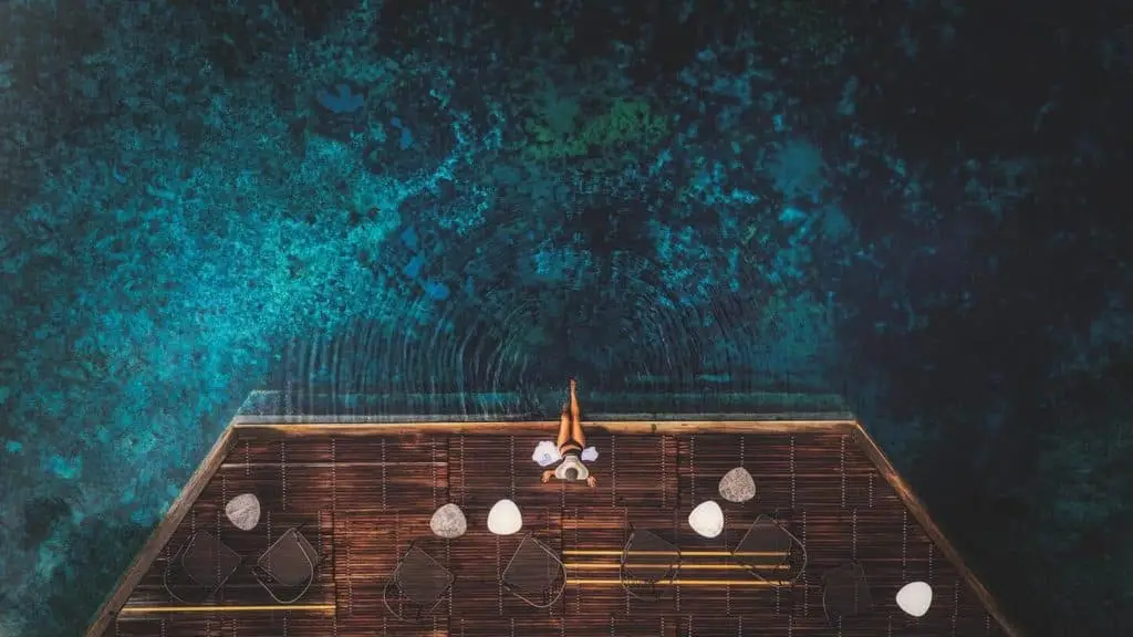 Donna rilassata su piattaforma di legno con vista sull'acqua turchese. Relax al Club.