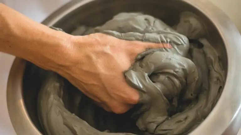 Mano che mescola fango termale detox in ciotola di metallo.