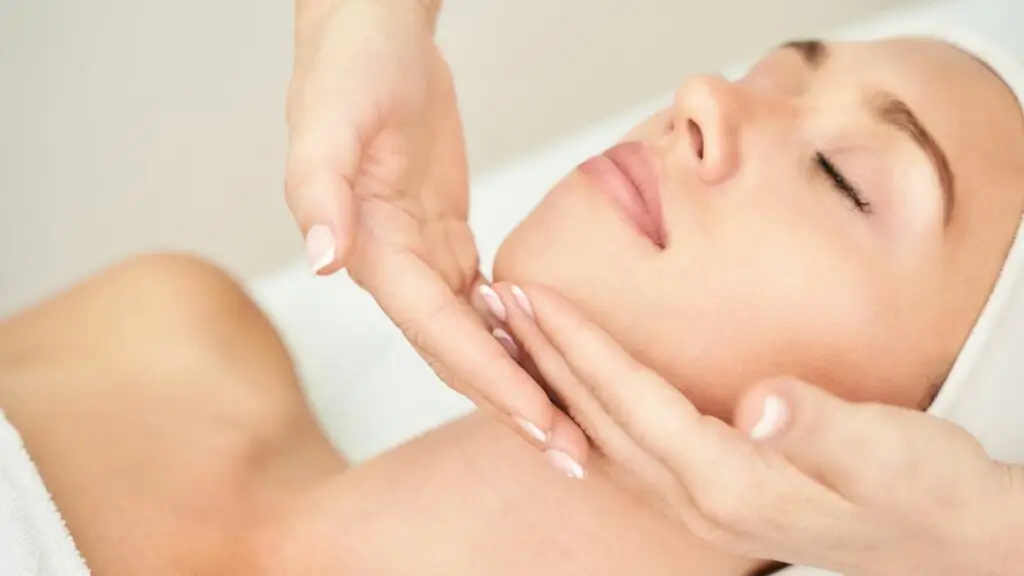 Donna che riceve massaggio Kobido viso. Trattamento rilassante e cura della pelle.