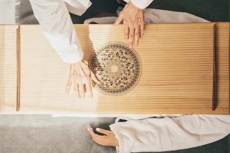 Terapista che esegue massaggio sonoro con cetra su paziente. Trattamento rilassante.