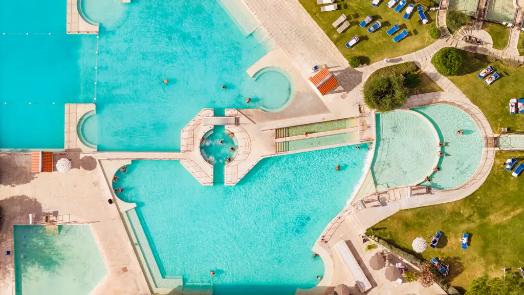 Vista aerea del Parco Termale con piscine turchesi e persone che nuotano. Relax e benessere termale.
