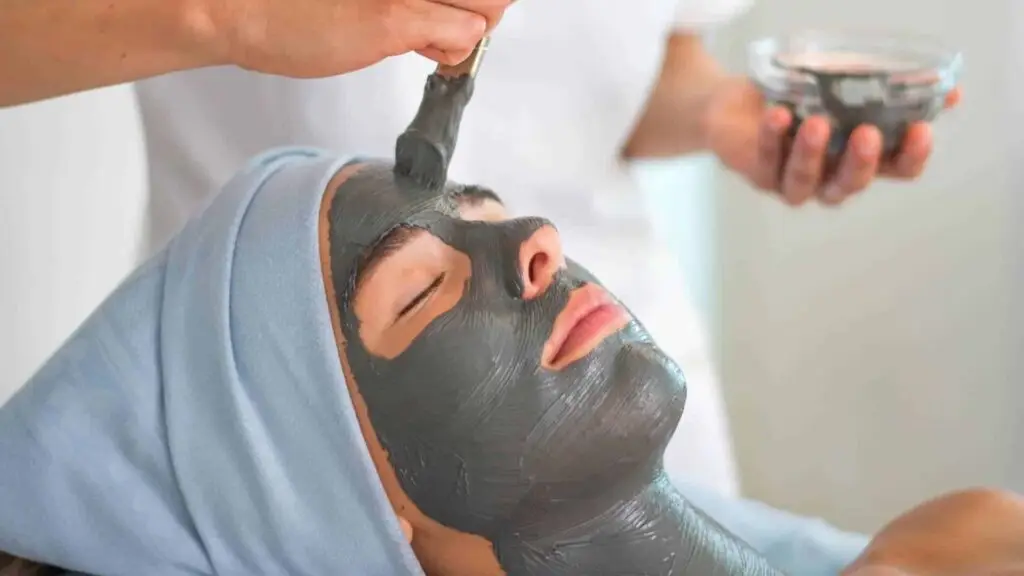Donna che riceve un trattamento termico viso con maschera grigia.