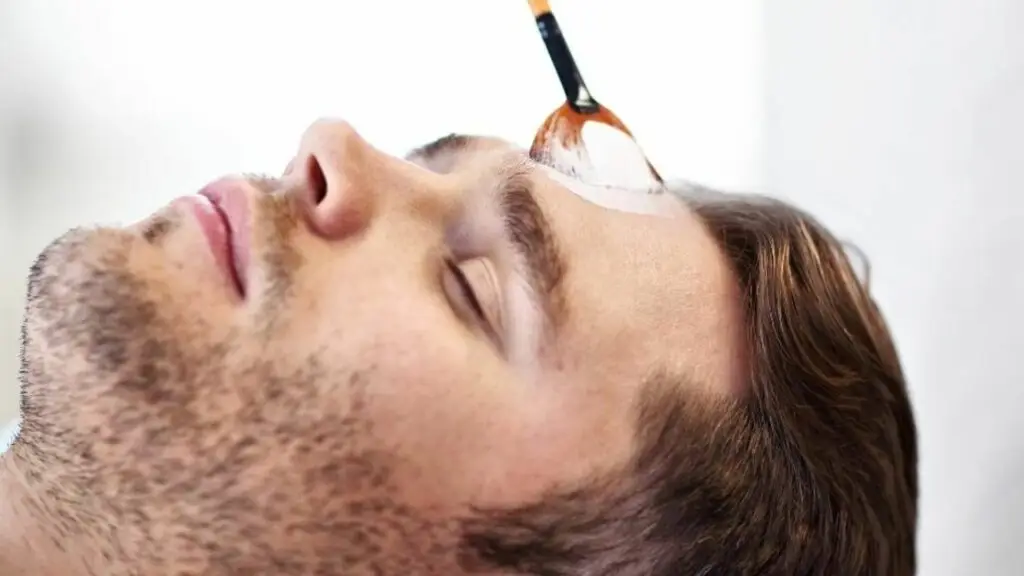 Uomo che riceve trattamento viso con pennello. Saturn for men.