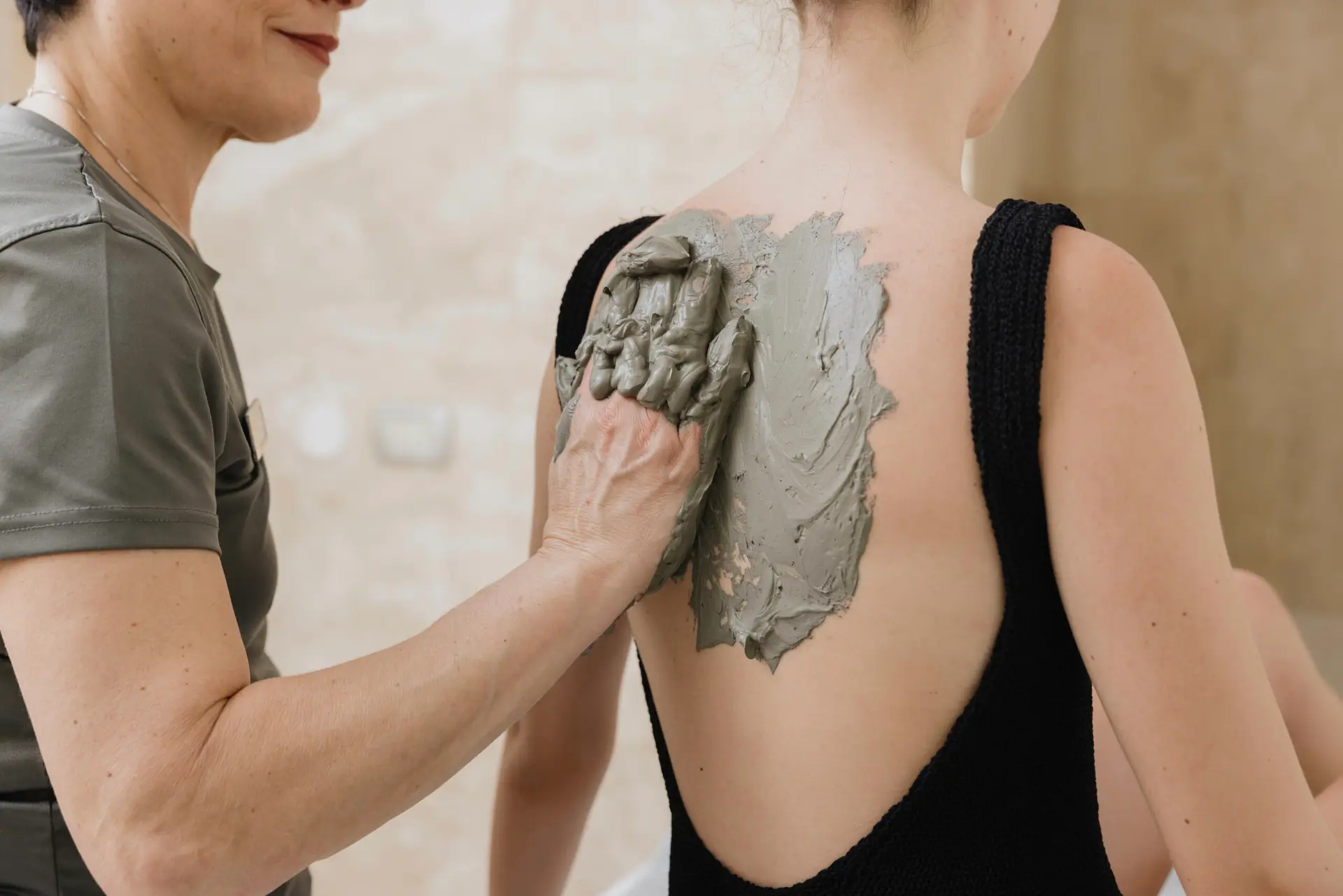 Applicazione di fango termale sulla schiena durante una cura termale. Spa e benessere.