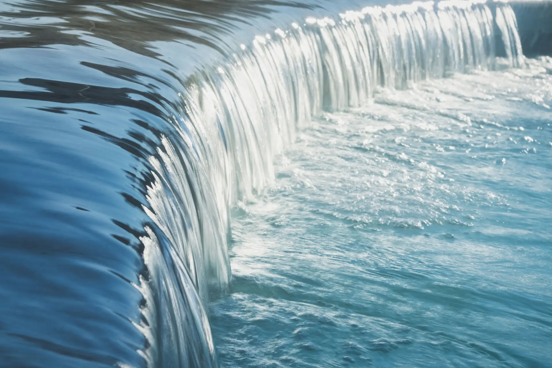 Cascata d'acqua turchese liscia che scorre su una diga.