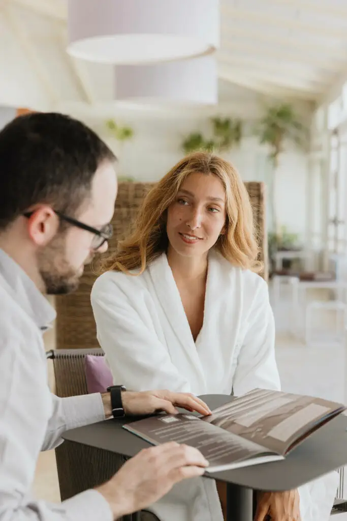 Donna in accappatoio consulta menù spa con addetto. Relax e benessere al Saturnia Day Spa.