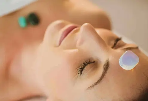Donna rilassata con cristalli sul viso. Trattamento di naturopatia per il benessere.