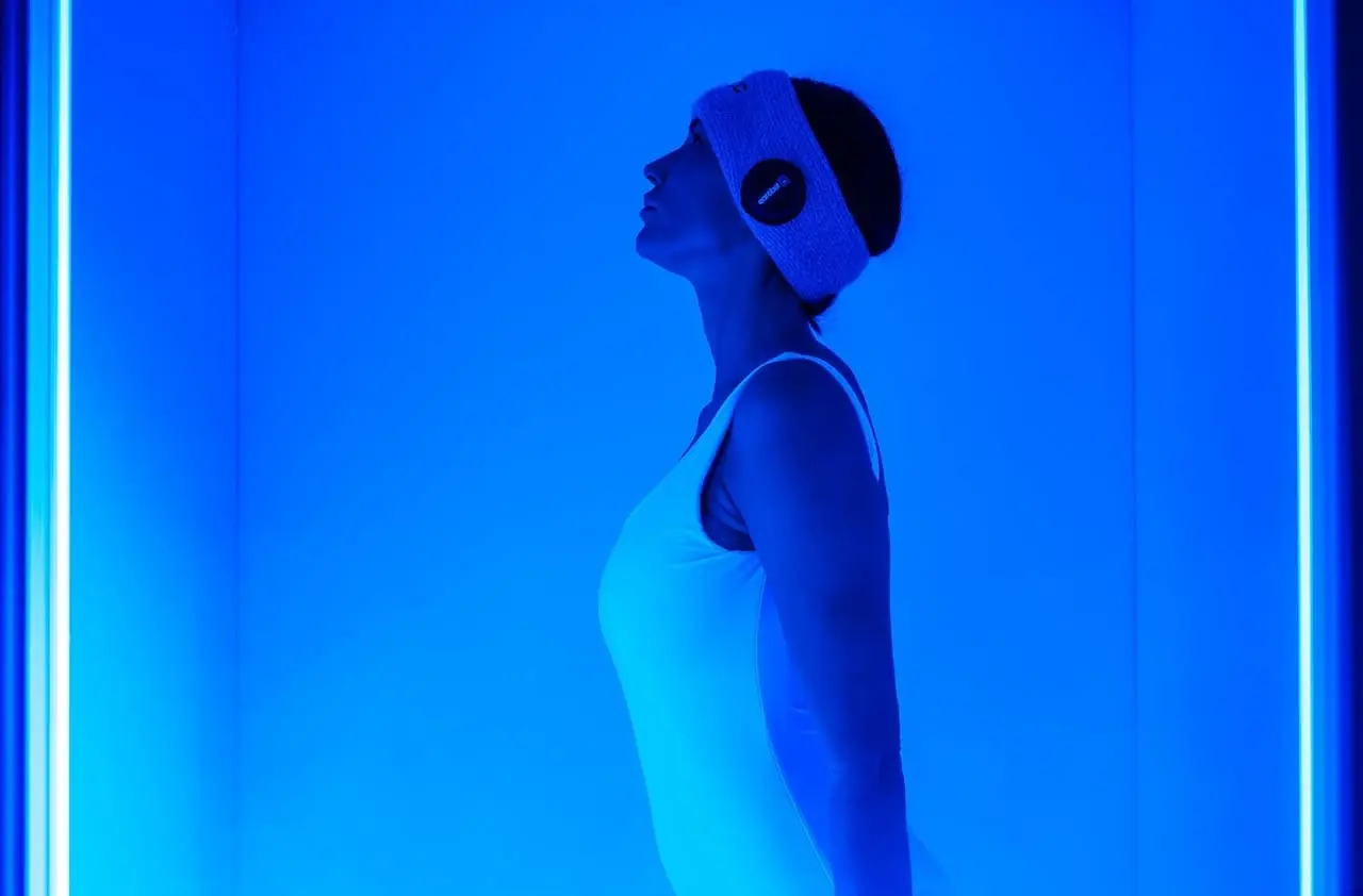 Donna con fascia per la testa sotto luce blu, possibile trattamento benessere o massaggio.