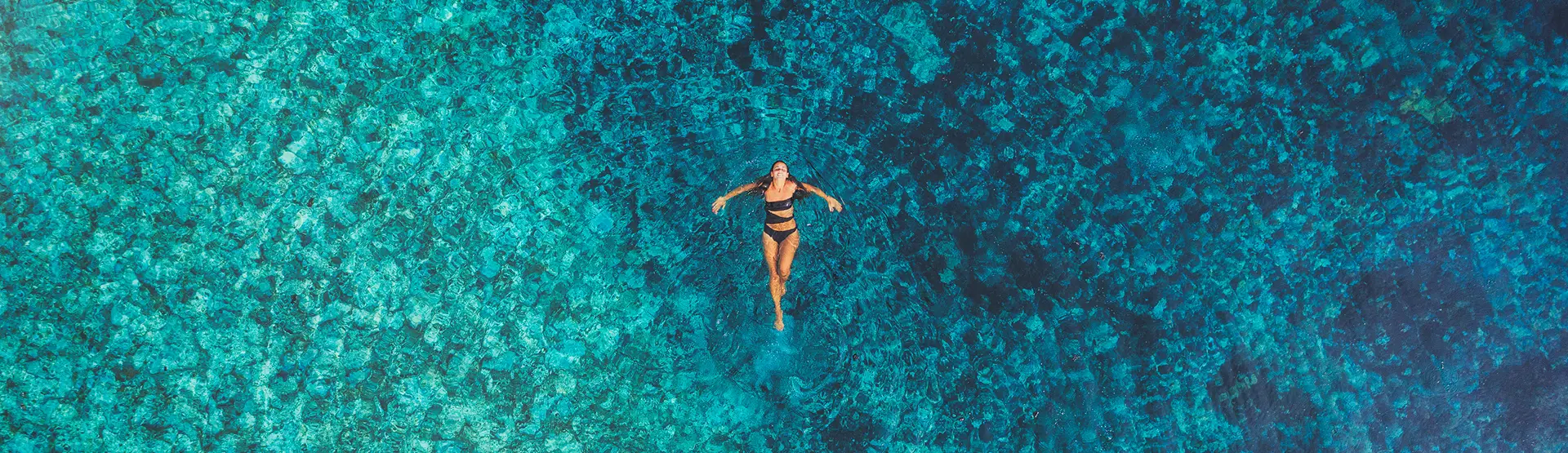 Donna che galleggia nell'acqua cristallina turchese. Relax in acqua termale.