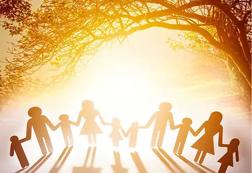 Sagome di famiglia che si tengono per mano sotto un albero illuminato dal sole. Concetto di naturopatia.