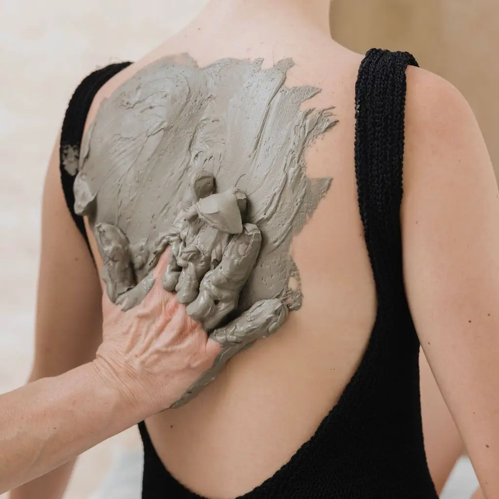 Applicazione di fango termale sulla schiena al Saturnia Day Spa. Trattamento benessere e relax.