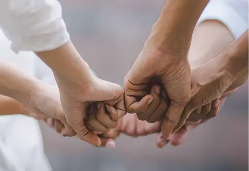 Mani che si toccano in segno di unione. Naturopatia e connessione umana.