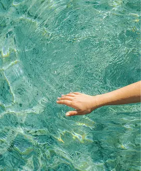 Mano che tocca l'acqua cristallina. Rinfrescante.