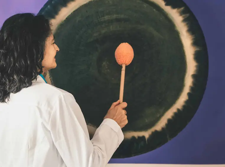 Naturopata suona gong terapeutico con mazza. Terapia del suono e benessere.