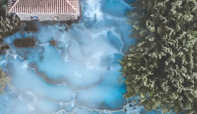 Terme di Saturnia, Toscana. Sorgenti termali naturali con acqua azzurra e vegetazione lussureggiante.