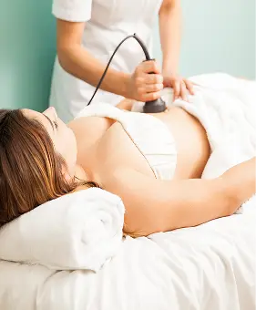 Trattamento corpo con ultrasuoni in centro medico. Donna riceve terapia per il corpo.