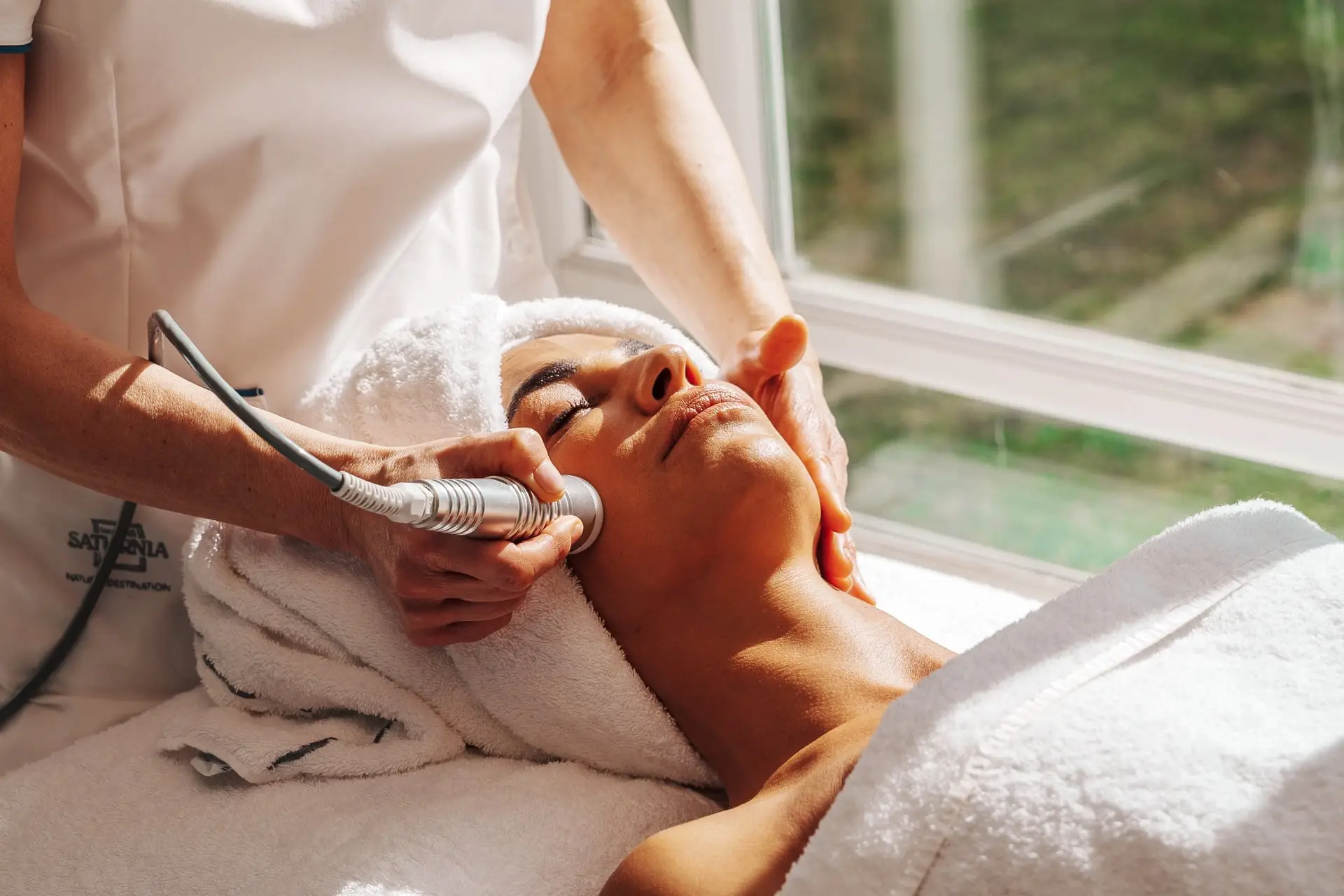 Donna che riceve un trattamento viso con massaggio e asciugamano in un centro benessere.