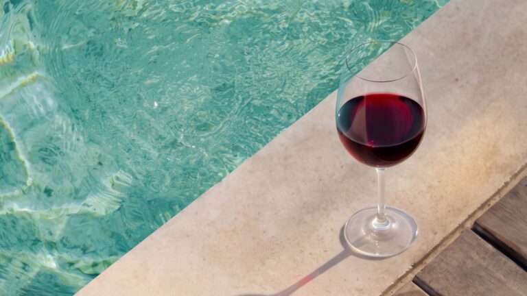 Calice di vino rosso accanto a una piscina